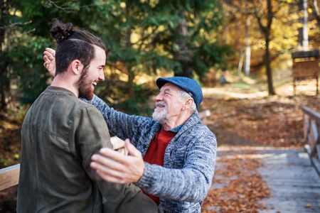 Senior father and his son on walk in nature, hugging and talking.の写真素材