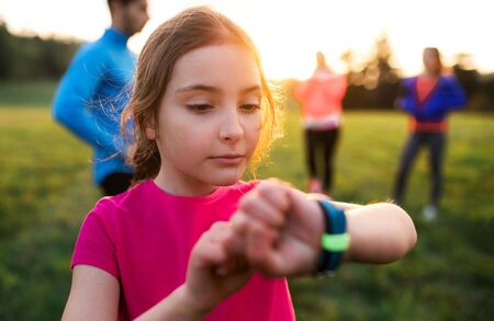 A portrait of small girl with large group of people doing exercise in nature.の写真素材