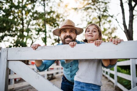 A portrait of father with small daughter outdoors on family farm.の写真素材