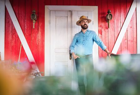 A portrait of mature man farmer standing outdoors in front of family farm.の写真素材