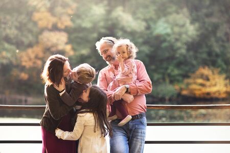 Beautiful young family with small children on a walk in autumn forest, resting.