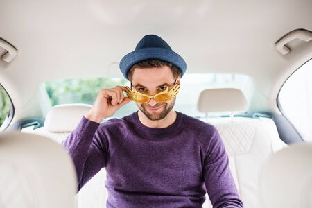 Cheerful man with party accessories sitting in car, having fun.