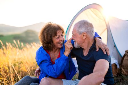 Senior tourist couple in love sitting in nature at sunset, resting.の写真素材