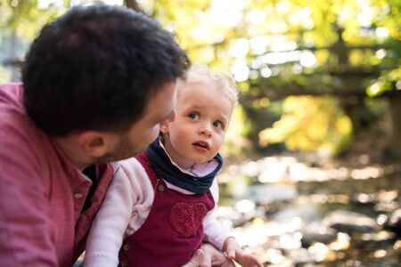 Father with small daughter on a walk in autumn forest, resting and talking.の写真素材