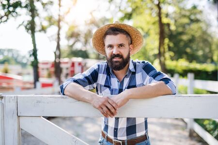 A portrait of mature man farmer standing outdoors on family farm.の写真素材