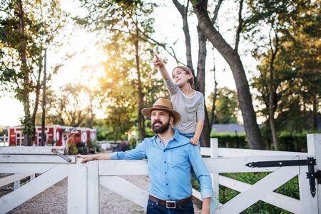 A portrait of father with small daughter outdoors on family farm.の写真素材