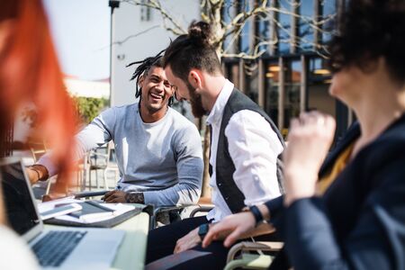 Young businesspeople with laptop in courtyard, start-up concept.の写真素材