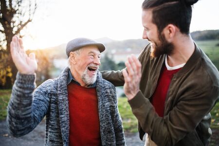 Laughing senior father and his son on walk in nature, giving high five.の写真素材