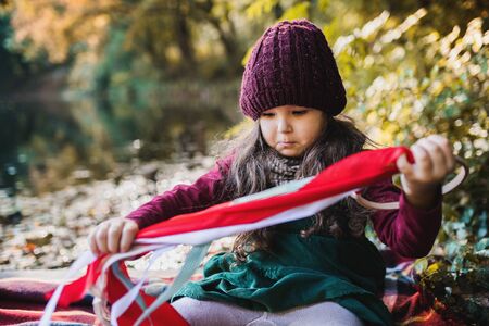 A portrait of a small toddler girl sitting in forest in autumn nature.の写真素材