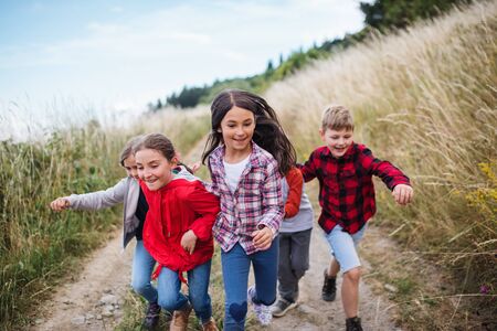 Group of school children running on field trip in nature.