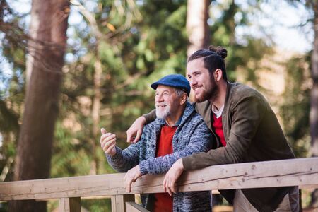 Senior father and his son on walk in nature, standing and talking.の写真素材