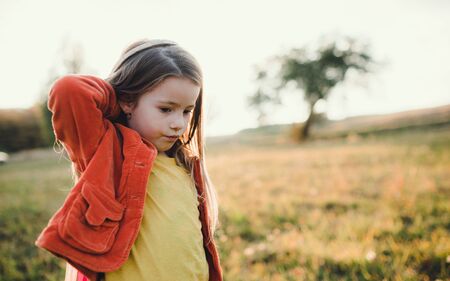 A small girl walking in autumn nature at sunset, playing.の写真素材