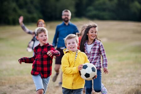 Group of school children with teacher on field trip in nature, playing with a ball.の写真素材