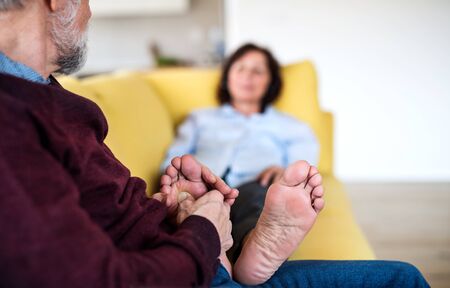 Affectionate senior couple in love sitting on sofa indoors at home, relaxing.