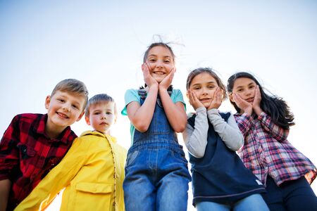Group of school children standing on field trip in nature, looking at camera.の写真素材
