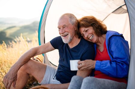 Senior tourist couple in love sitting in nature at sunset, resting.の写真素材