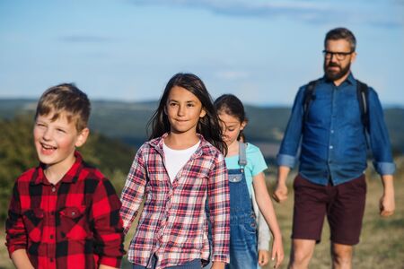Group of school children with teacher on field trip in nature, walking.