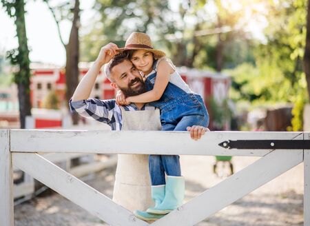 A portrait of father with small daughter outdoors on family farm.の写真素材