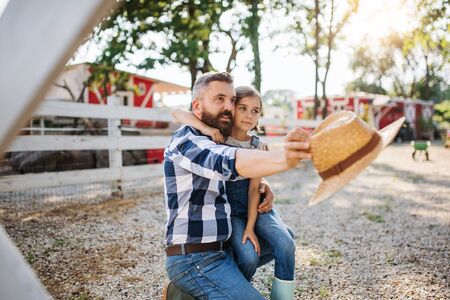 A father with small daughter outdoors on family farm, talking.の写真素材