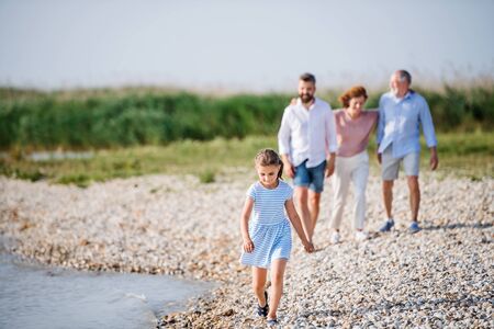 Multigeneration family on a holiday walking by the lake, holding hands.の写真素材