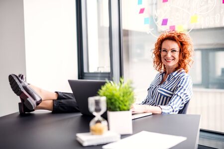 A portrait of businesswoman resting in an office, holding a cup of coffee.