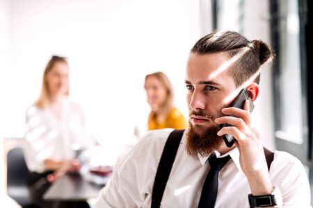 A portrait of young businessman with smartphone in an office, making call.の写真素材