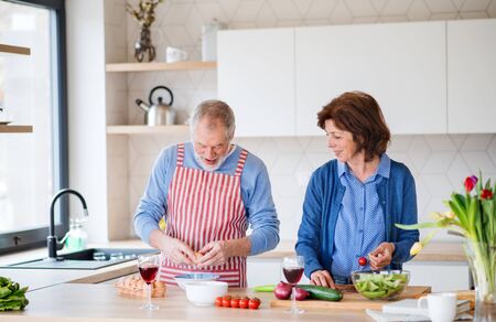 A portrait of senior couple indoors at home, cooking.の写真素材