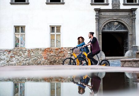 Young tourist couple travellers with electric scooters in small town.