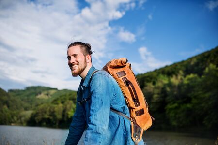 Young tourist man traveller with backpack standing in nature, resting.