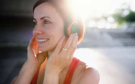 A close-up of young woman runner with headphones in city, resting.の写真素材