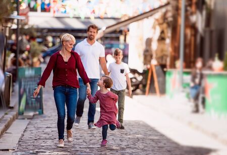 Young family with two small children walking outdoors in town on holiday.の写真素材