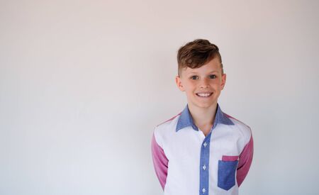 A portrait of small boy standing against white background.の写真素材