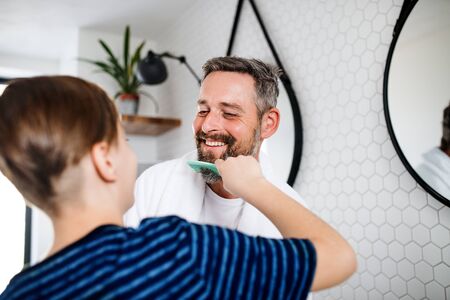 Mature father with small son in the bathroom in the morning, combing.の写真素材
