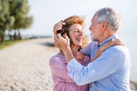 Senior couple on a holiday on a walk by the lake, hugging.の写真素材