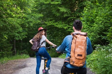 Rear view of young tourist couple travellers with electric scooters in nature.の写真素材