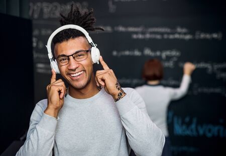 Young businessman with headphones in office, listening to music.