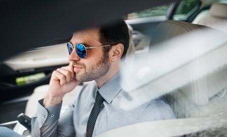 Young businessman with shirt and tie sitting in car.