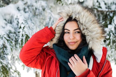 A front view portrait of young woman standing outdoors in snowy winter forest.の写真素材