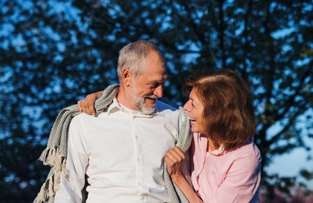 Beautiful senior couple in love outside in spring nature at dusk, talking.の写真素材