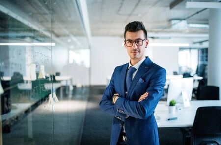 A portrait of young businessman standing in an office, arms crossed.の写真素材