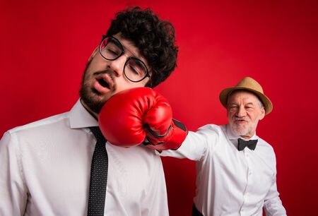 Studio shot of young versus old generation, a father and son with boxing glove.