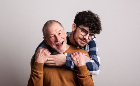 Portrait of a cheerful senior father and young son in a studio.の写真素材