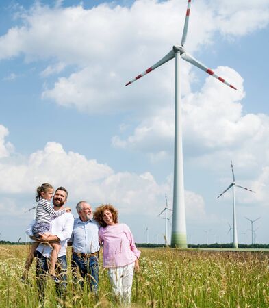 Multigeneration family standing on field on wind farm.の写真素材