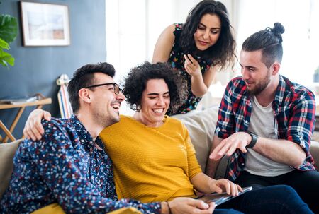 A group of young friends with tablet indoors, house sharing concept.