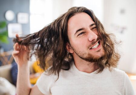 A portrait of young man with long hair indoors, a close-up.の写真素材