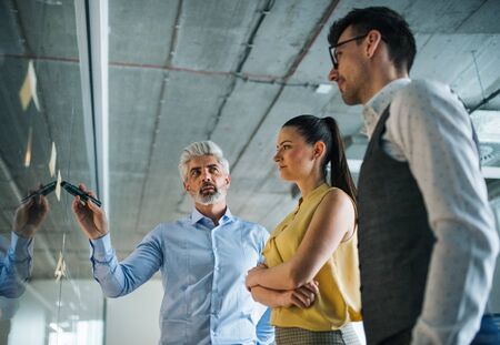 A group of business people standing in an office, brainstorming.の写真素材