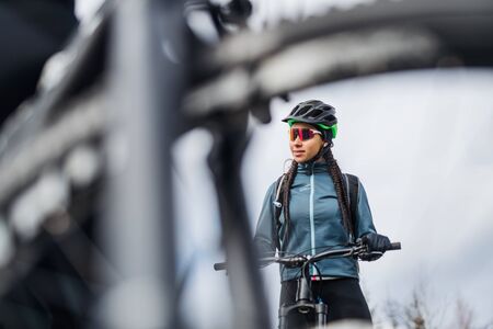 Female mountain biker standing on road outdoors in winter.の写真素材