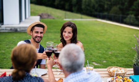 Portrait of people with wine outdoors on family garden barbecue.の写真素材