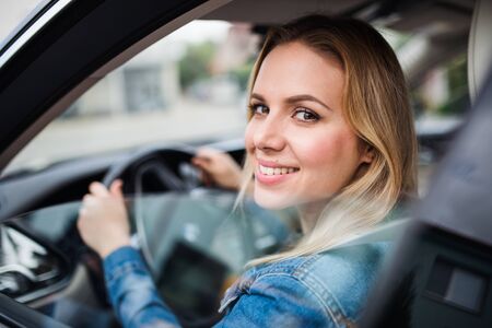 Young woman driver sitting in car, looking out.