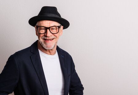 Portrait of a senior man with hat and glasses in a studio. Copy space.